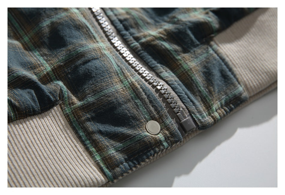 Detailed view of the jacket's gray zipper, snap fastener, plaid fabric, and beige rib-knit hem.
