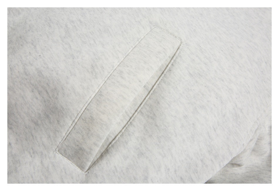 Close-up of an angled welt pocket on the light gray hoodie.