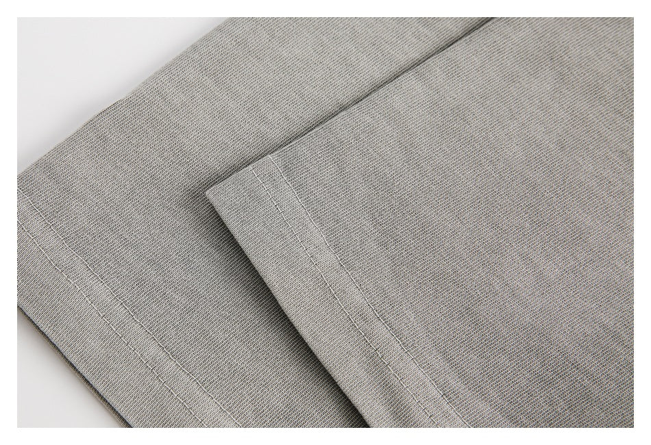 Close-up of layered gray knit fabric with parallel stitched hems.