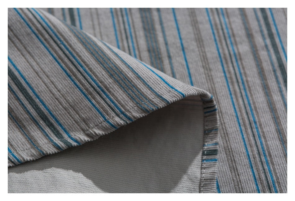 Close-up of a folded edge on gray fabric with narrow blue and charcoal stripes.