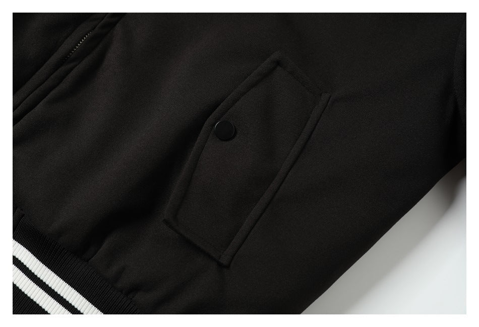Close-up of a black flap pocket with a snap on the jacket, above a striped ribbed hem.