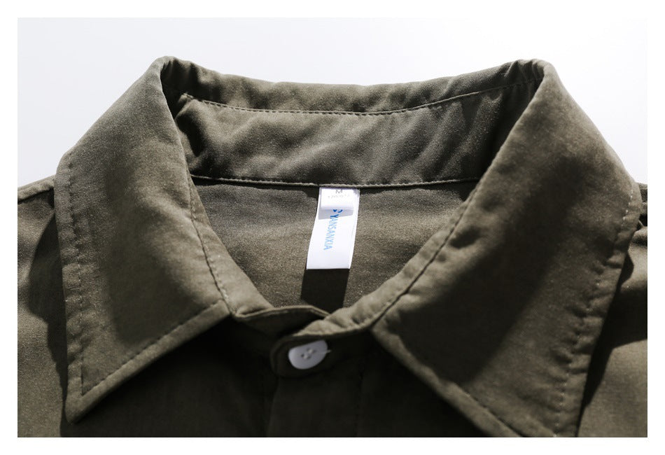 Close-up of an olive shirt collar, white button, and inner neck label.