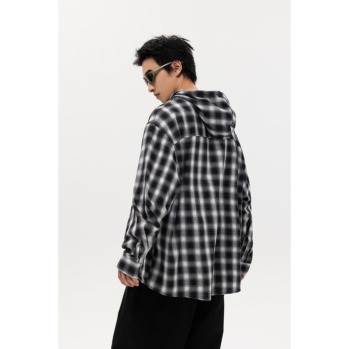 Back view of a model wearing a black-and-white plaid hooded button-up shirt.