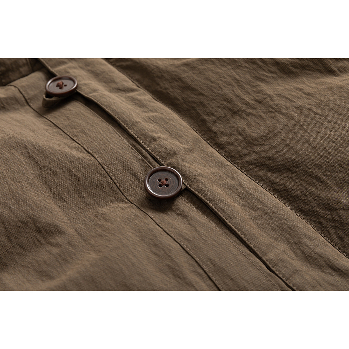 Close-up of a brown jacket's textured fabric and front placket with two dark brown buttons.