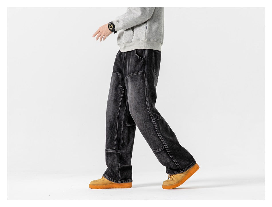 Inset side view of a model walking in loose black washed jeans with contrast panel seams.