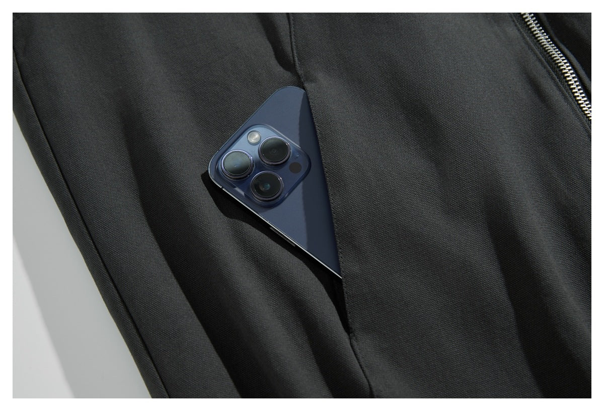 Close-up of a phone tucked into a pocket on charcoal jacket fabric.