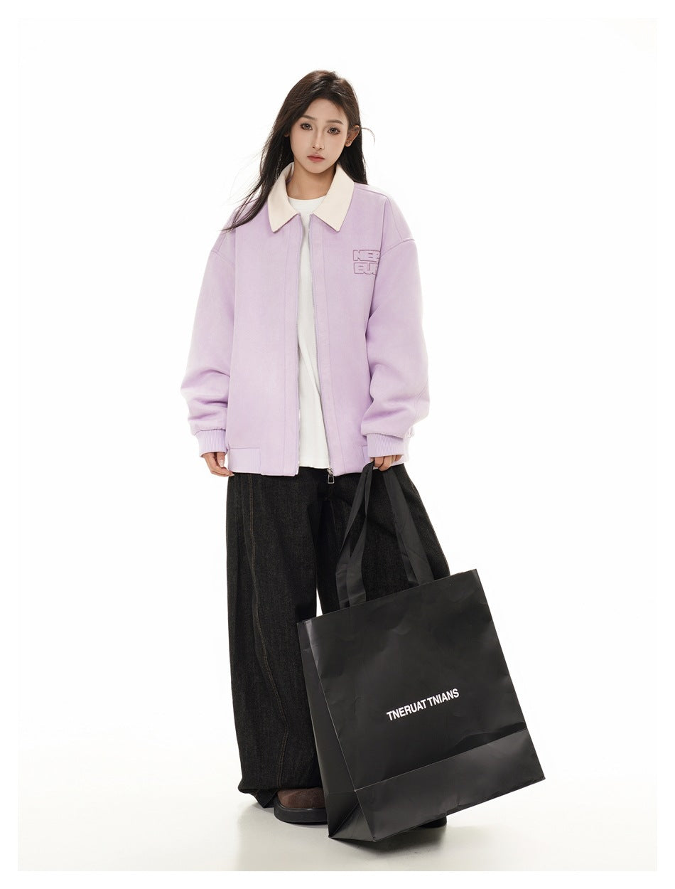 Model wearing lavender zip jacket with cream collar over a white tee and wide dark pants, holding a black shopping bag