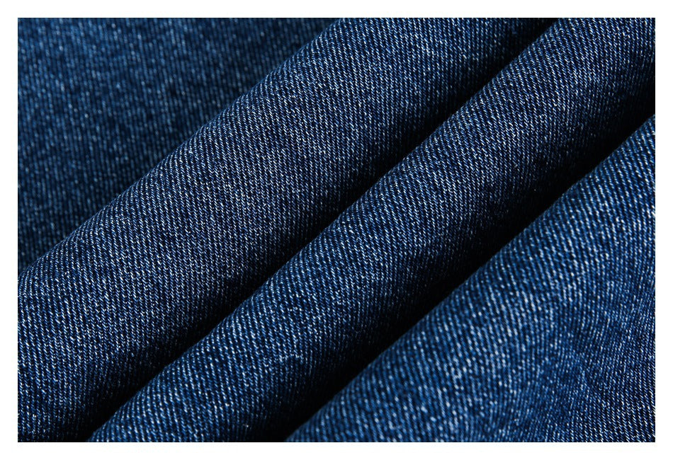 Macro view of dark blue denim fabric folded to show its diagonal weave.