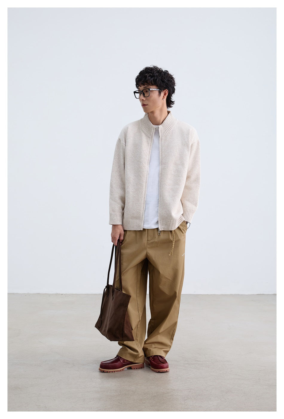 Full-length view of a man wearing an open ivory zip-front knit sweater with a ribbed collar and cuffs.