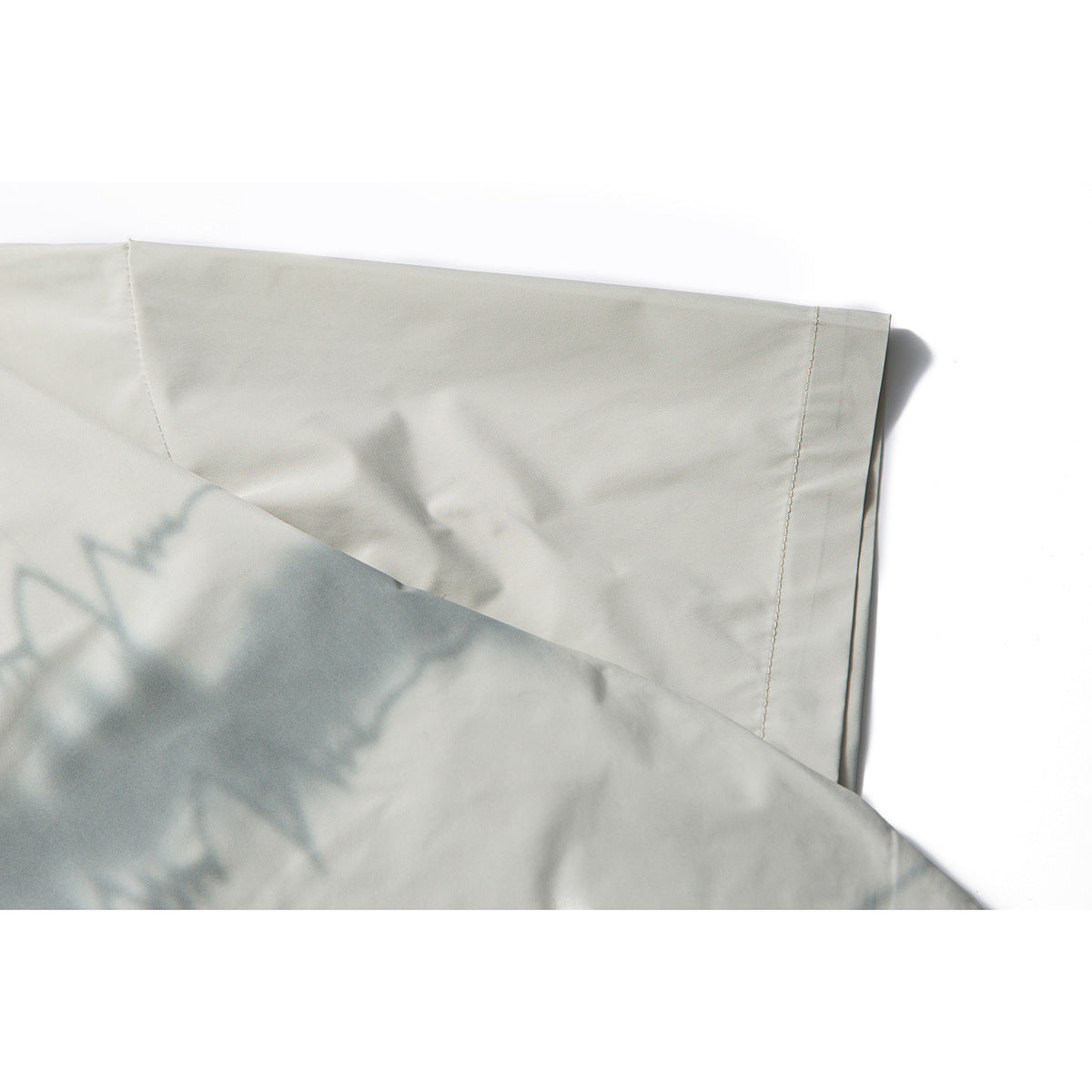 Close-up of an off-white shirt sleeve and stitched cuff with soft shadows.