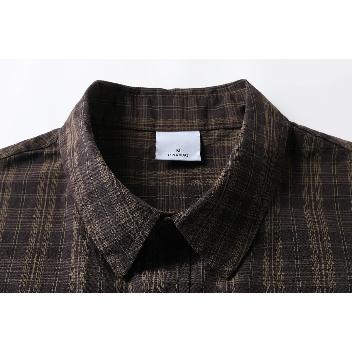 Close-up of a dark brown plaid shirt collar and inner size label.