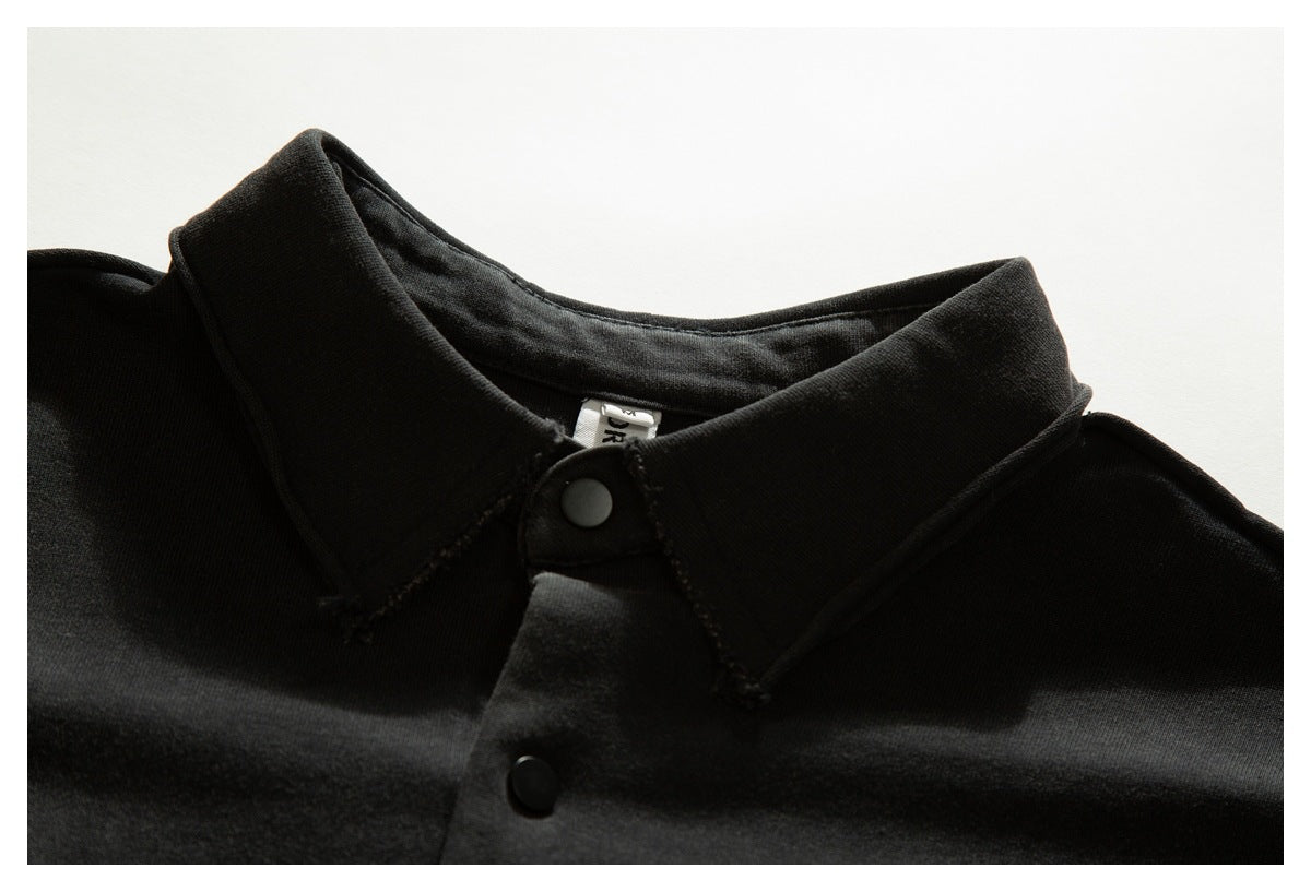 Close-up of a black shirt collar, snap buttons, and a partially visible inner label.