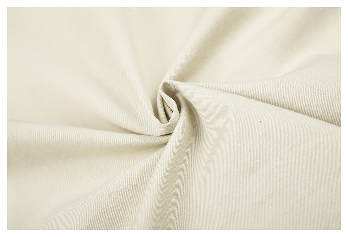 Close-up of ivory fabric gathered into a twist, showing its fine diagonal weave.