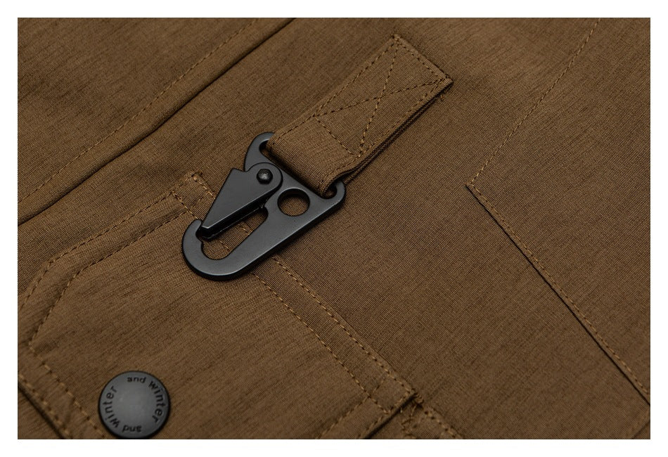 Close-up of a black clip fastened to a stitched loop on the brown coat, beside a flap pocket.