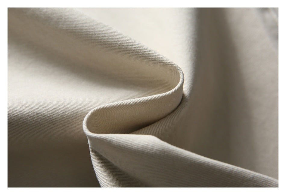 Close-up of pale beige fabric draped to show its fine diagonal weave and texture.