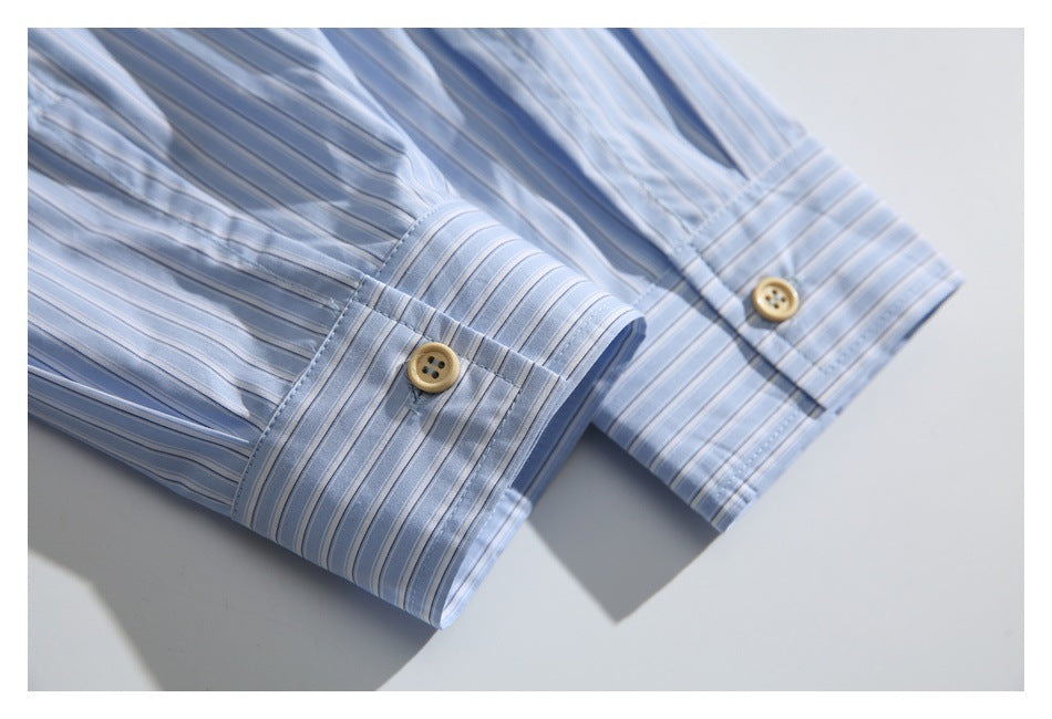 Close-up of two buttoned cuffs on a light blue shirt with narrow stripes.