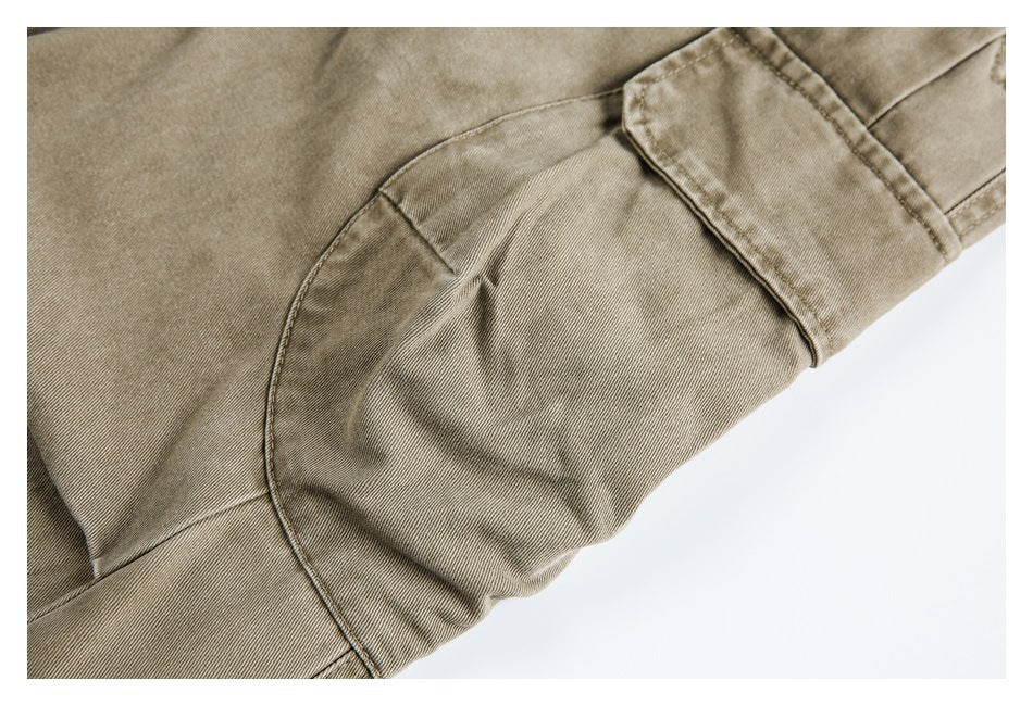 Close-up of khaki trousers showing a curved seam and stitched panel details.