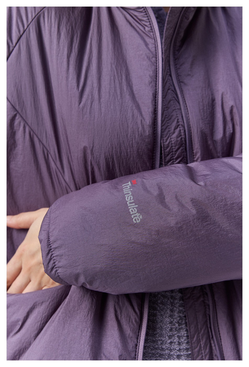 Close-up of a purple jacket sleeve with Thinsulate branding beside the front zipper and pocket.