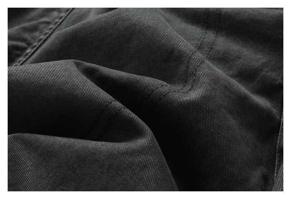 Close-up of dark charcoal fabric with diagonal texture and stitched seams.