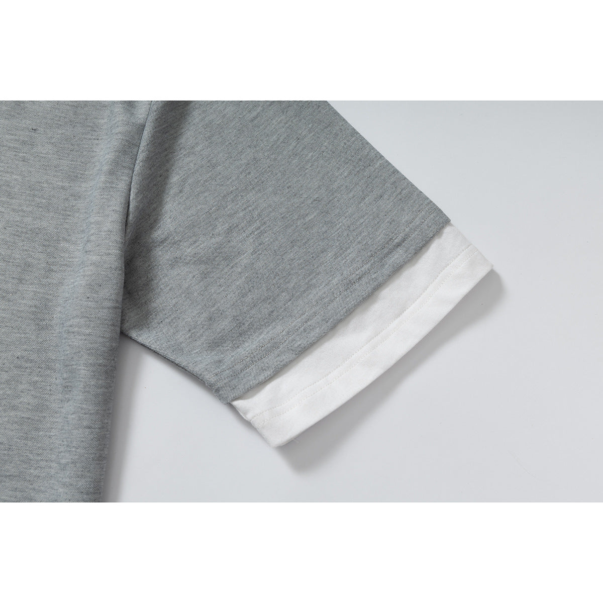 Close-up of a gray short sleeve finished with a wide white cuff band.