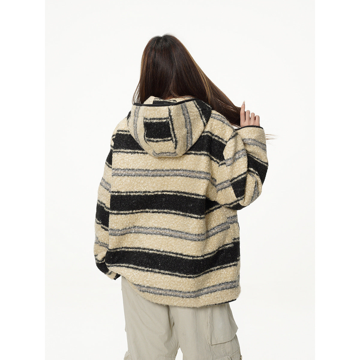 Back view of a model wearing a cream, black, and gray striped hooded jacket with beige cargo pants.