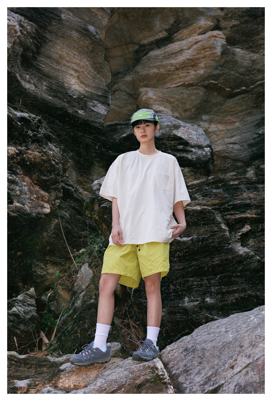 Front view of a model wearing a white pocket T-shirt and bright yellow hiking shorts.