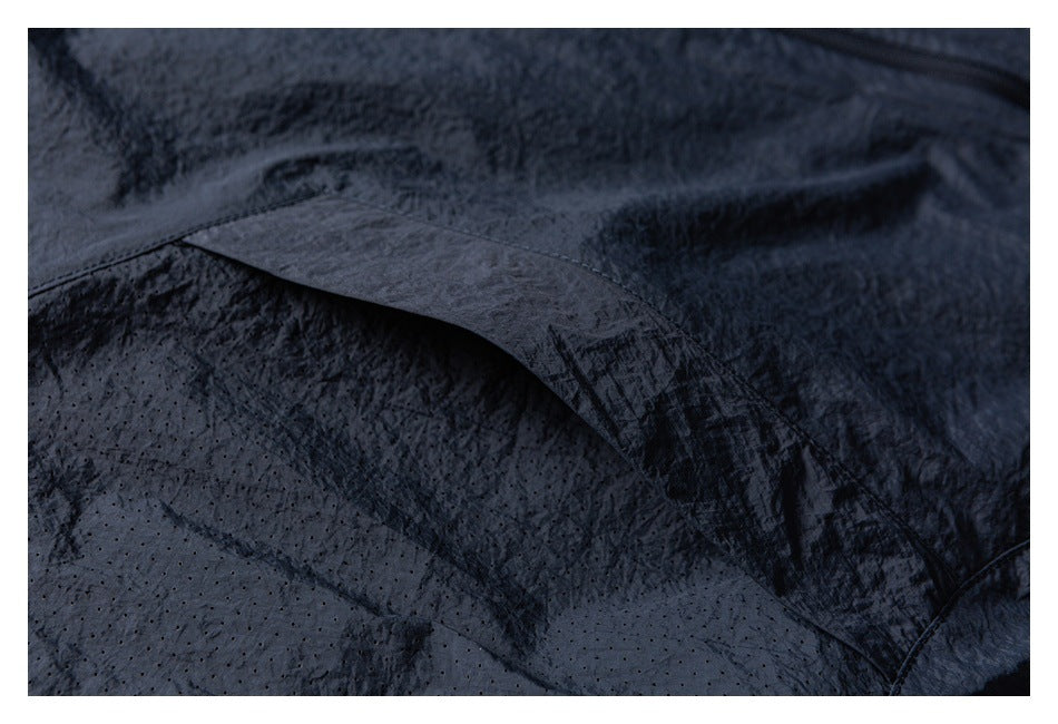 Close-up of a dark jacket's stitched overlapping panel and perforated fabric.