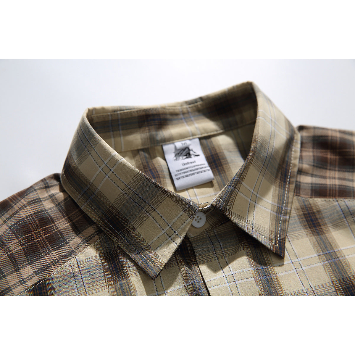 Close-up of a tan and brown plaid shirt collar, button, and inner neck label.