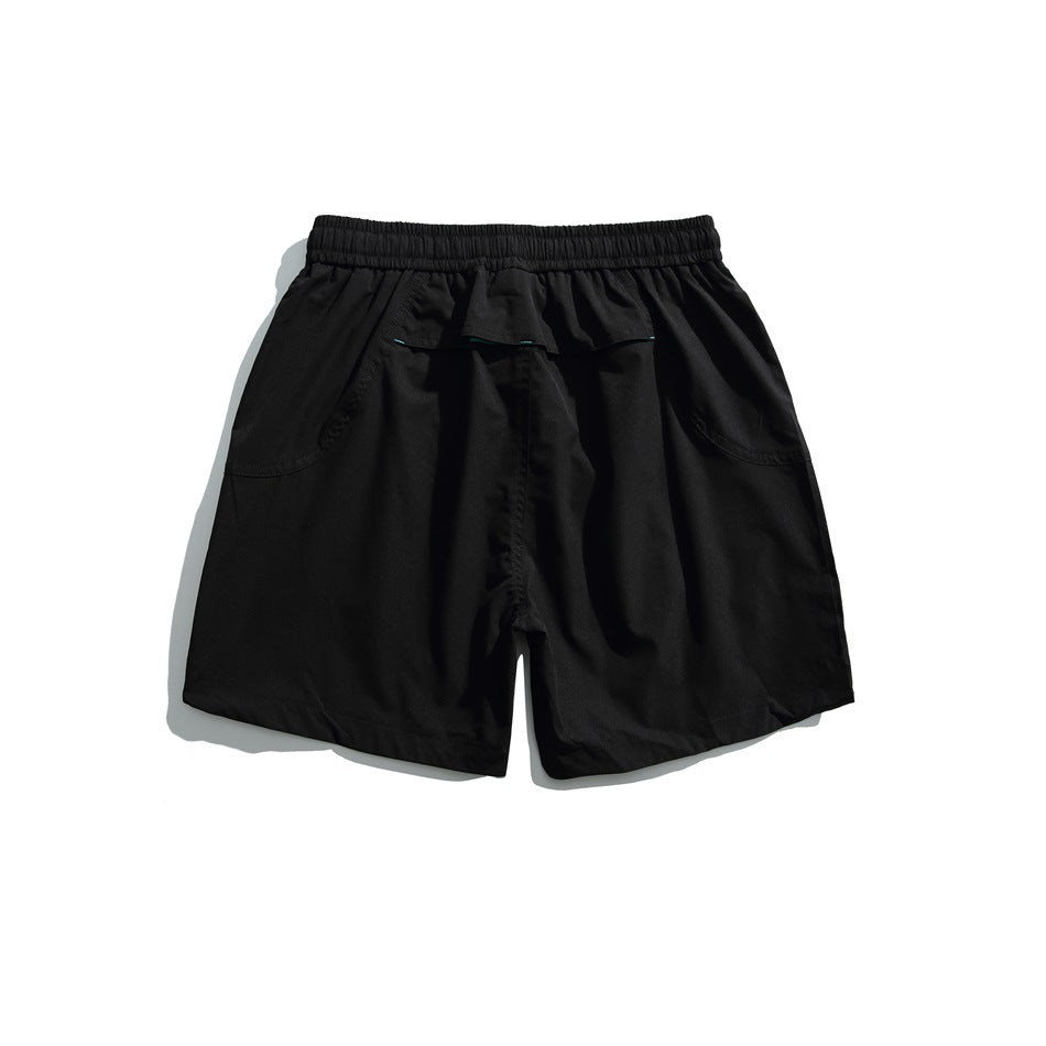 Black athletic shorts shown from the back, with an elastic waistband, flap pocket, and curved side pockets.