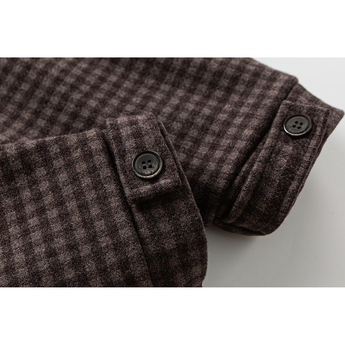 Close-up of dark buttons on the cuffs of a brown check jacket.