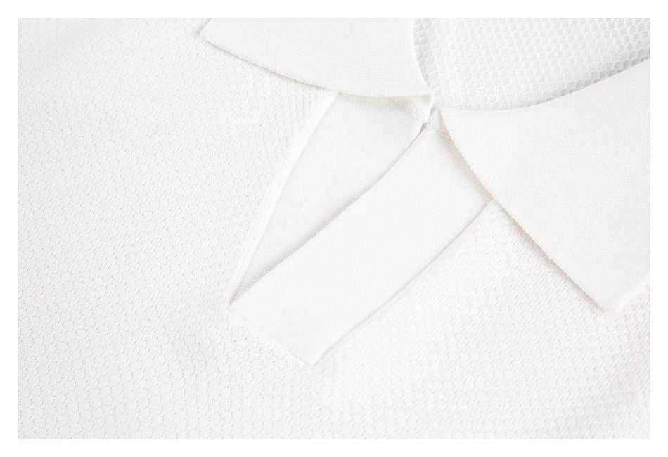 Close-up of the white knit polo shirt's pointed collar and open placket.