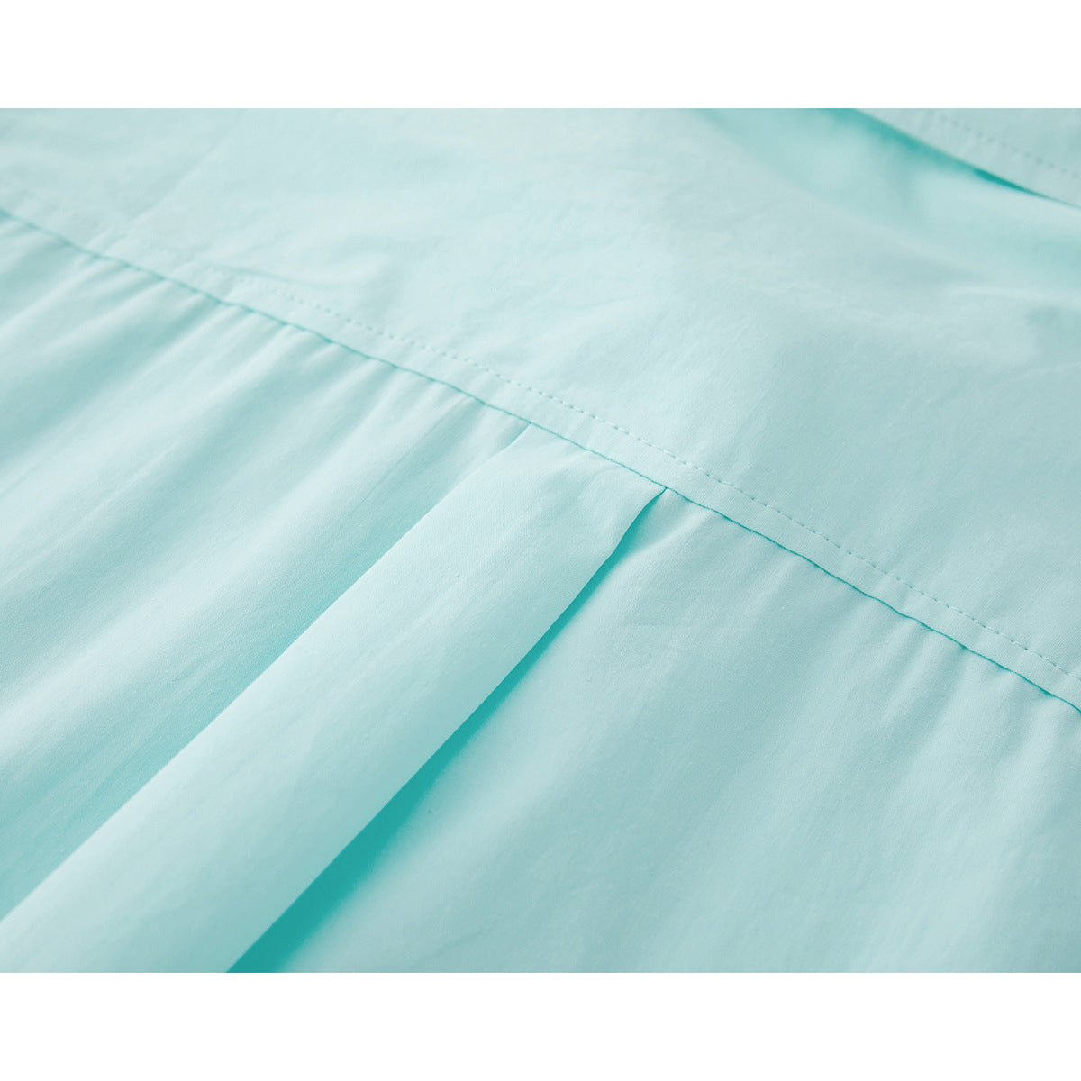 Close-up of the pale aqua shirt's back yoke seam and center pleat.