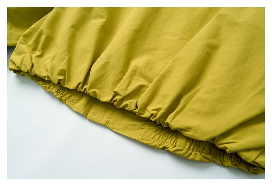 Close-up of the gathered elastic hem of a mustard-yellow garment.