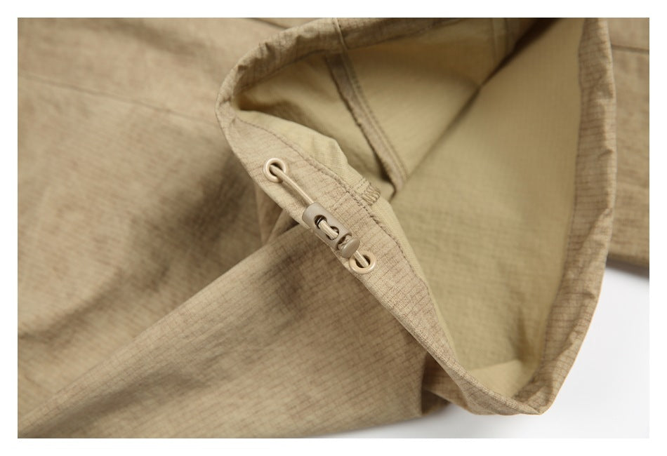 Inside close-up of a tan garment opening with a cord-and-toggle adjuster.