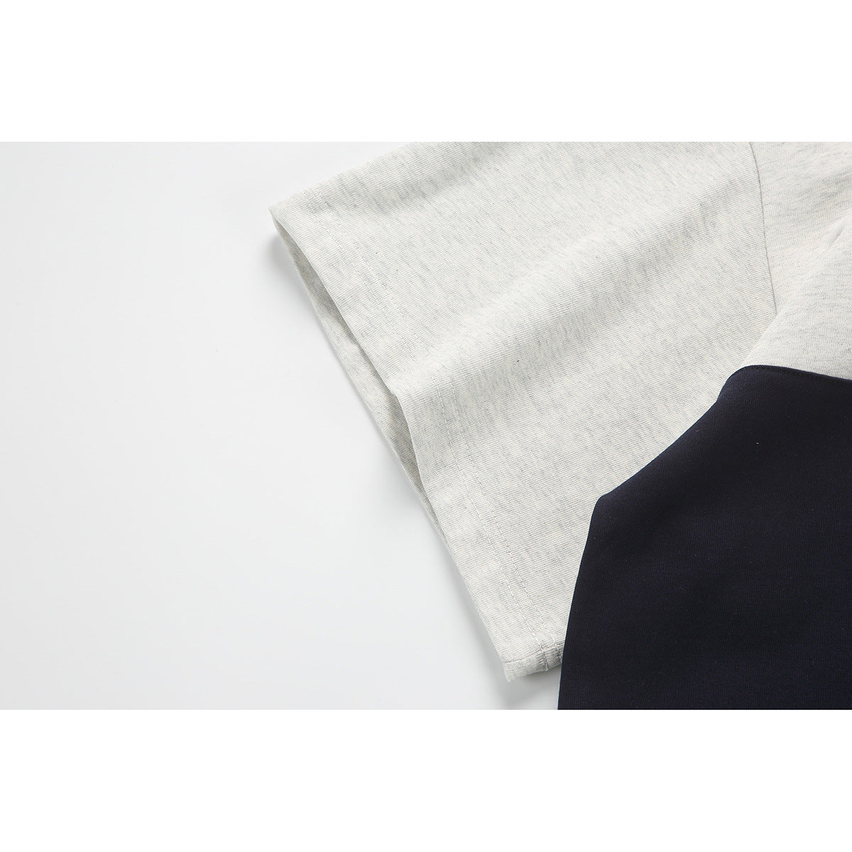 Close-up of the light gray sleeve and navy body of a color-block polo shirt.