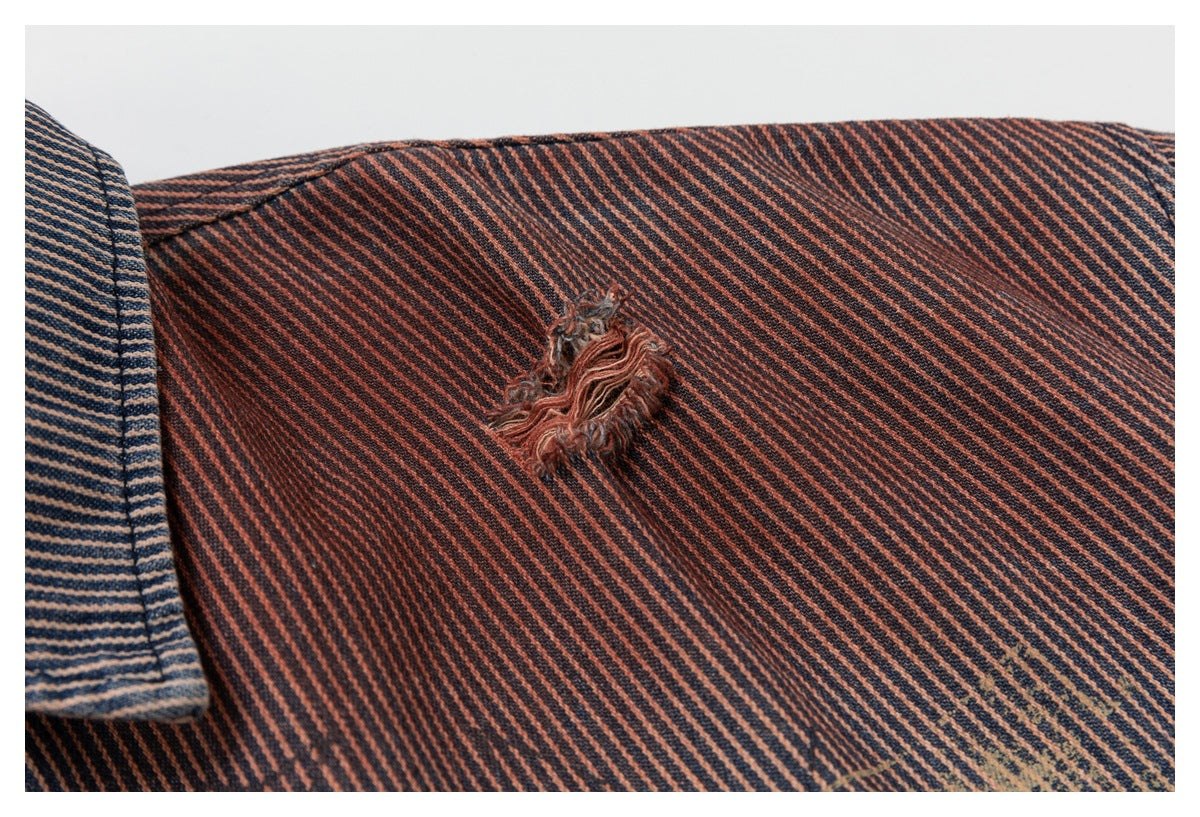 Close-up of a rust-and-dark pinstriped shirt jacket showing a frayed distressed patch and faded marking.