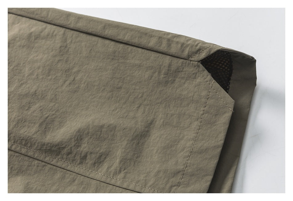 Close-up of a taupe garment corner with curved stitching and dark dotted mesh visible inside.