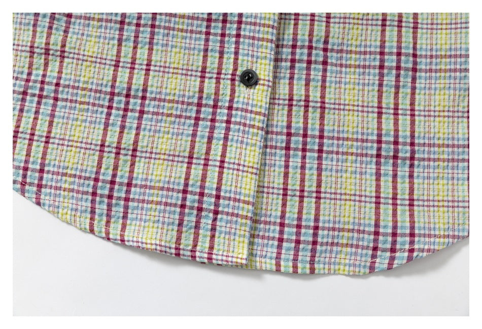 Close-up of the curved bottom hem and button placket of a multicolor plaid shirt.