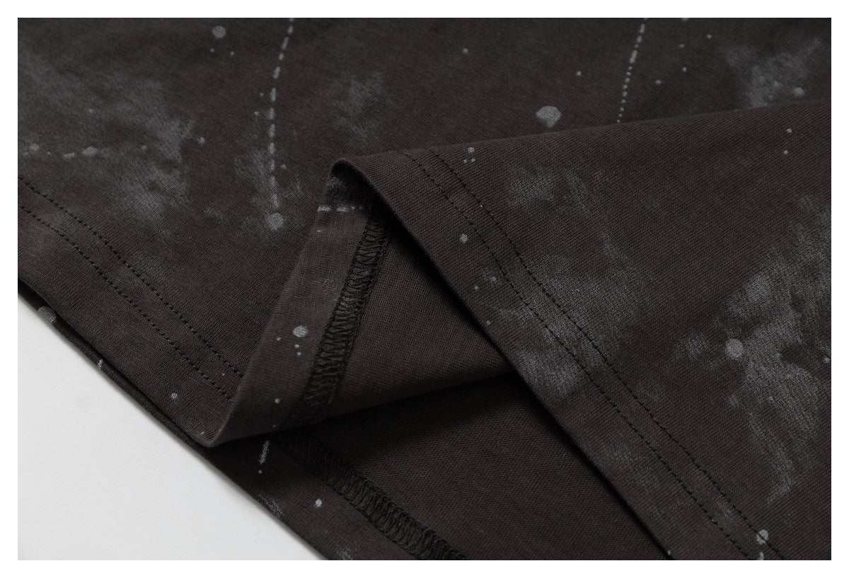 Close-up of folded garment edges showing dark splatter-print fabric and overlocked stitching.