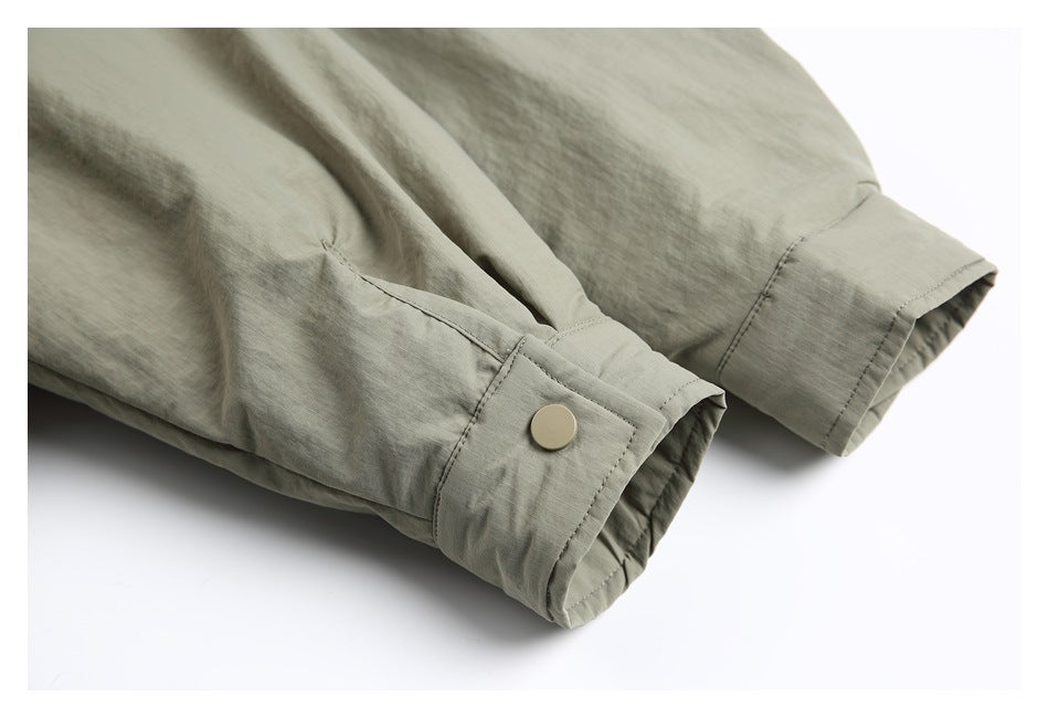 Close-up of sage-gray shirt cuffs with a pale button and stitched cuff placket.