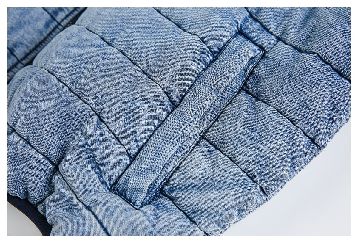 Close-up of light blue quilted jacket fabric with a stitched diagonal tab.