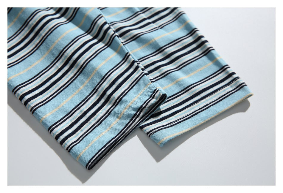 Close-up of two finished edges of light blue striped knit fabric, with black, white, and thin tan stripes.