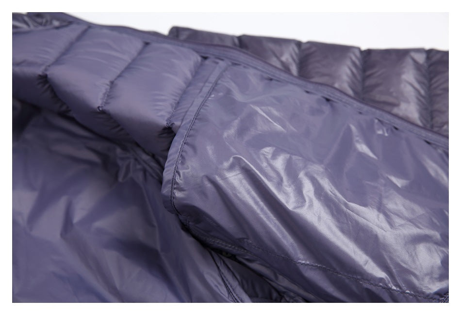 Close-up of a dark slate-purple jacket showing quilted padding and a smooth fabric panel with stitched seams.