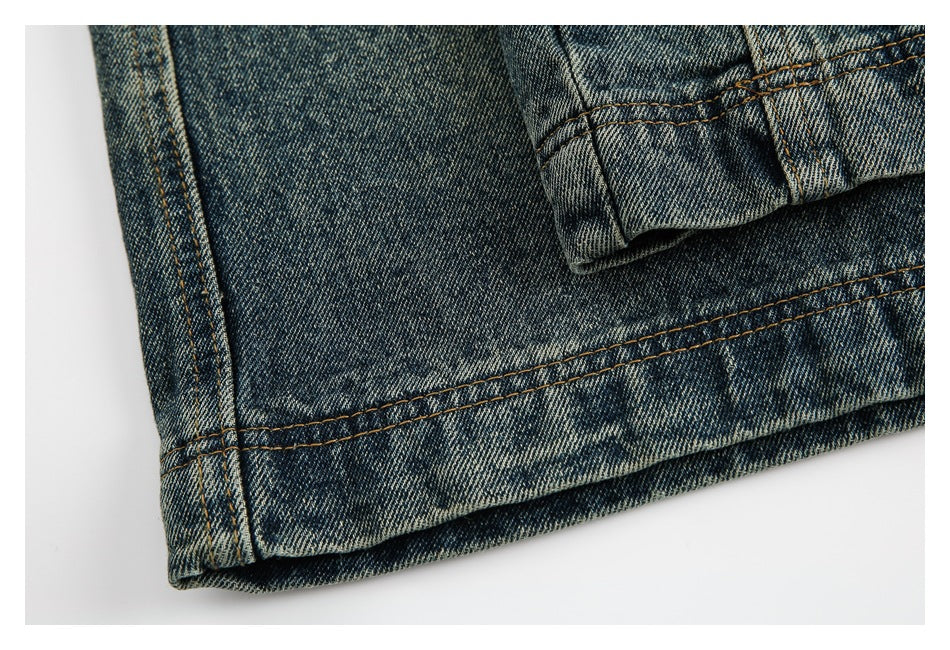 Close-up of the stitched hem and folded cuff of faded blue denim jeans.