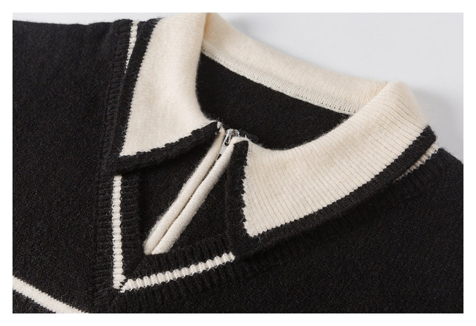 Close-up of a black sweater's ivory pointed collar, striped V-neck trim and short zipper.
