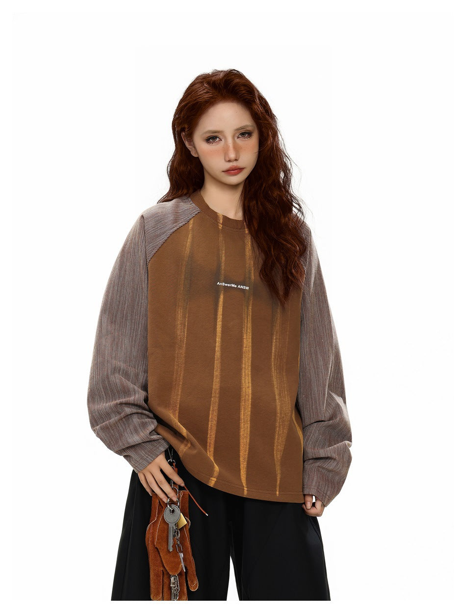 Front view of a model wearing a brown top with gold vertical stripes and oversized gray pinstriped raglan sleeves.
