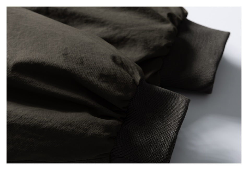 Close-up of an olive jacket sleeve gathered into a dark ribbed cuff.