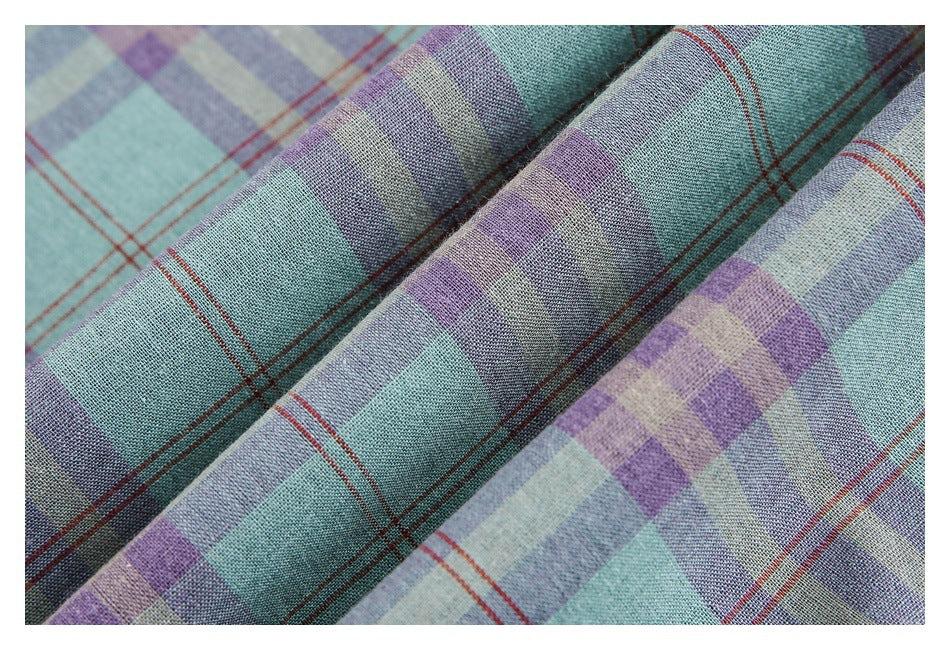 Close-up of the textured mint, lavender, and gray plaid fabric draped in folds, with thin rust-red lines.