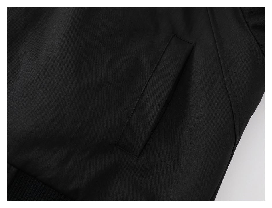 Close-up of a slanted welt pocket and panel seams on the dark jacket.