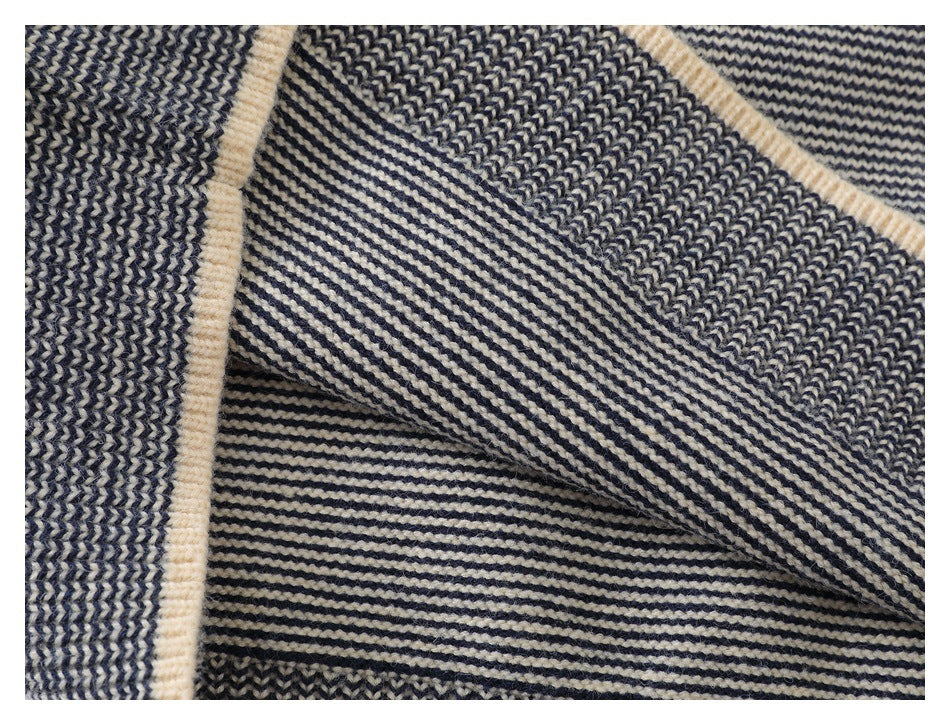 Close-up of layered navy and cream striped knit fabric with cream trim along a folded edge.